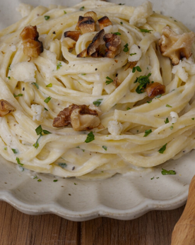 A plate of creamy pasta garnished with walnuts and herbs