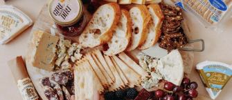 Organic Cheeses, Jams, and Crackers on wooden cutting board
