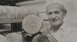 Man holding a circle wheel of blue cheese
